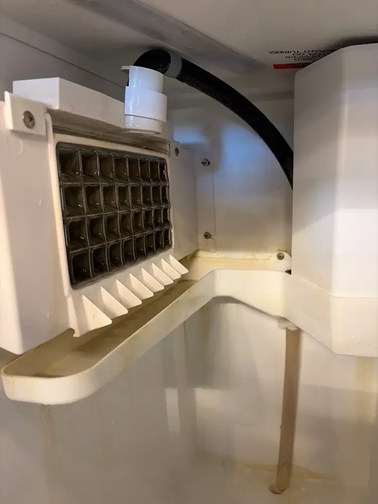 U-Line undercounter ice machine ice grid and chute with mineral and rust staining before cleaning, Lehi, Utah.